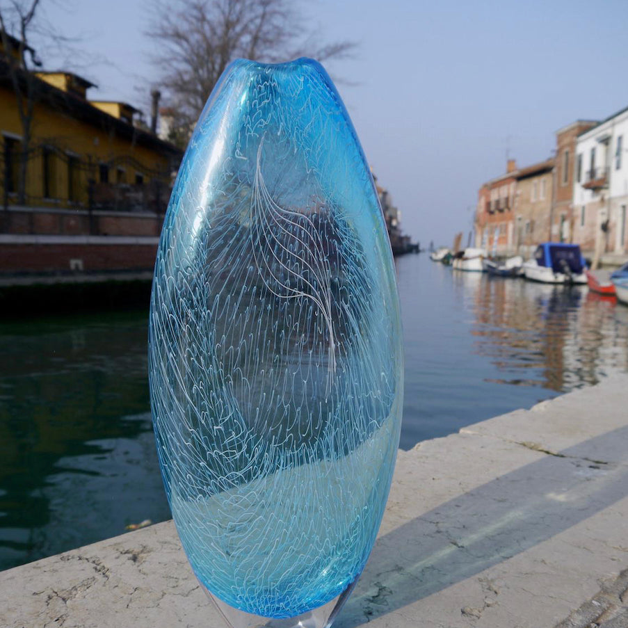 Tall blue glass vase photographed at the side of a canal in Venice by UK glass artist Benjamin Lintell, represented by the Byre Gallery, Cornwall 