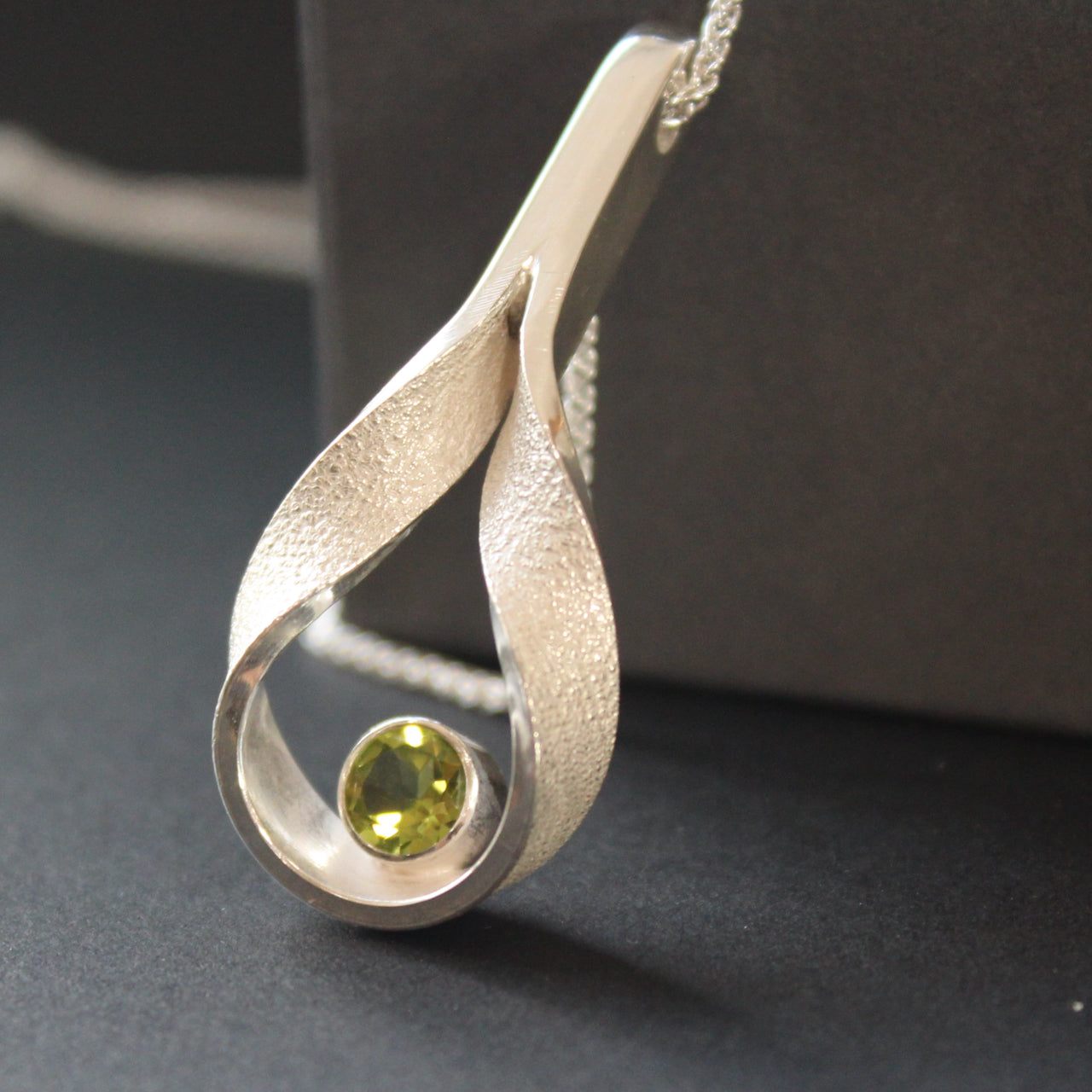 Drop curved hollow pendant set with peridot by artist Beverly Bartlett.