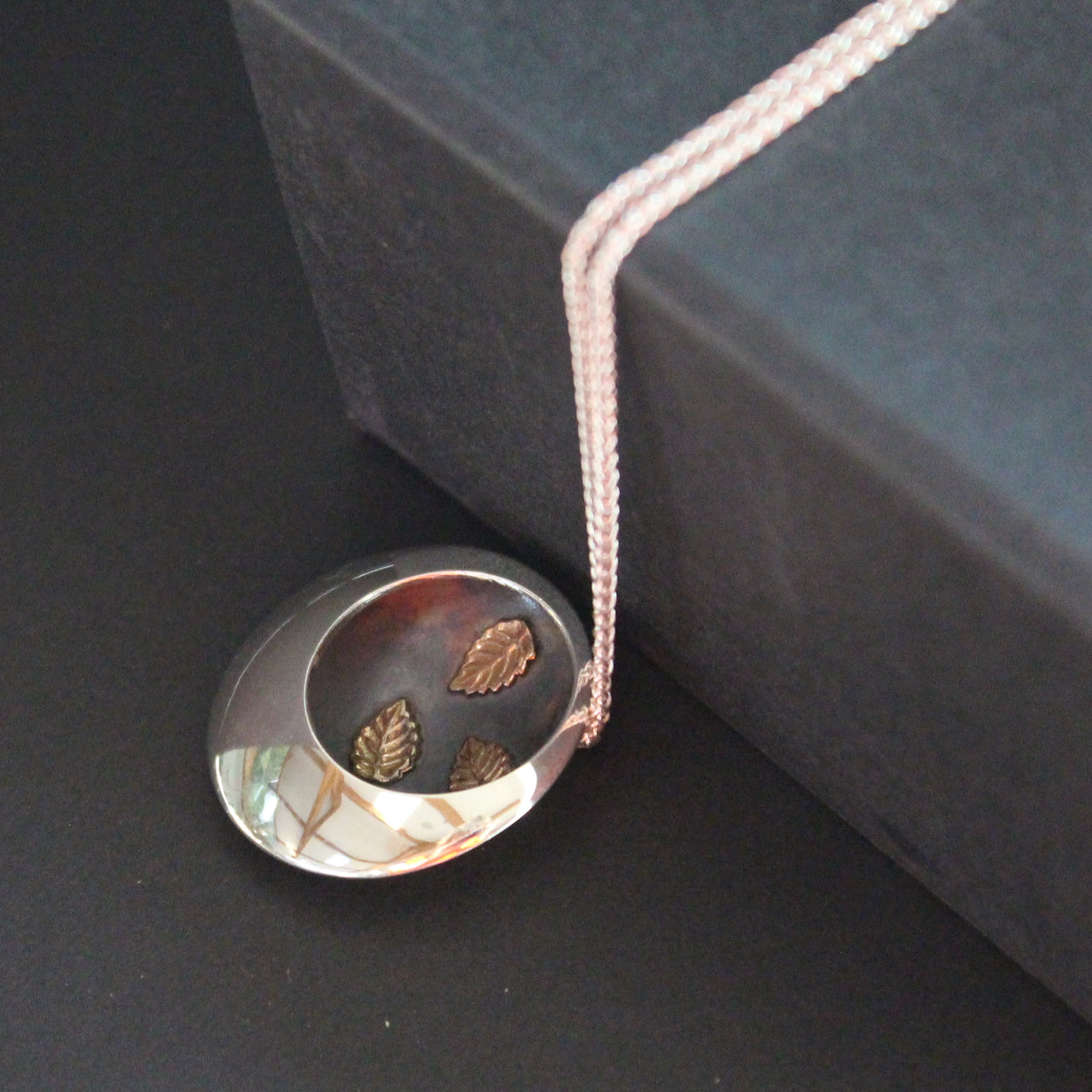 Silver round pendant with 3 inlayed leaves by UK artist Beverly Bartlett