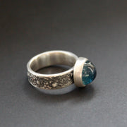 A Carin Lindberg textured silver ring with a round dark blue stone in a brushed silver setting