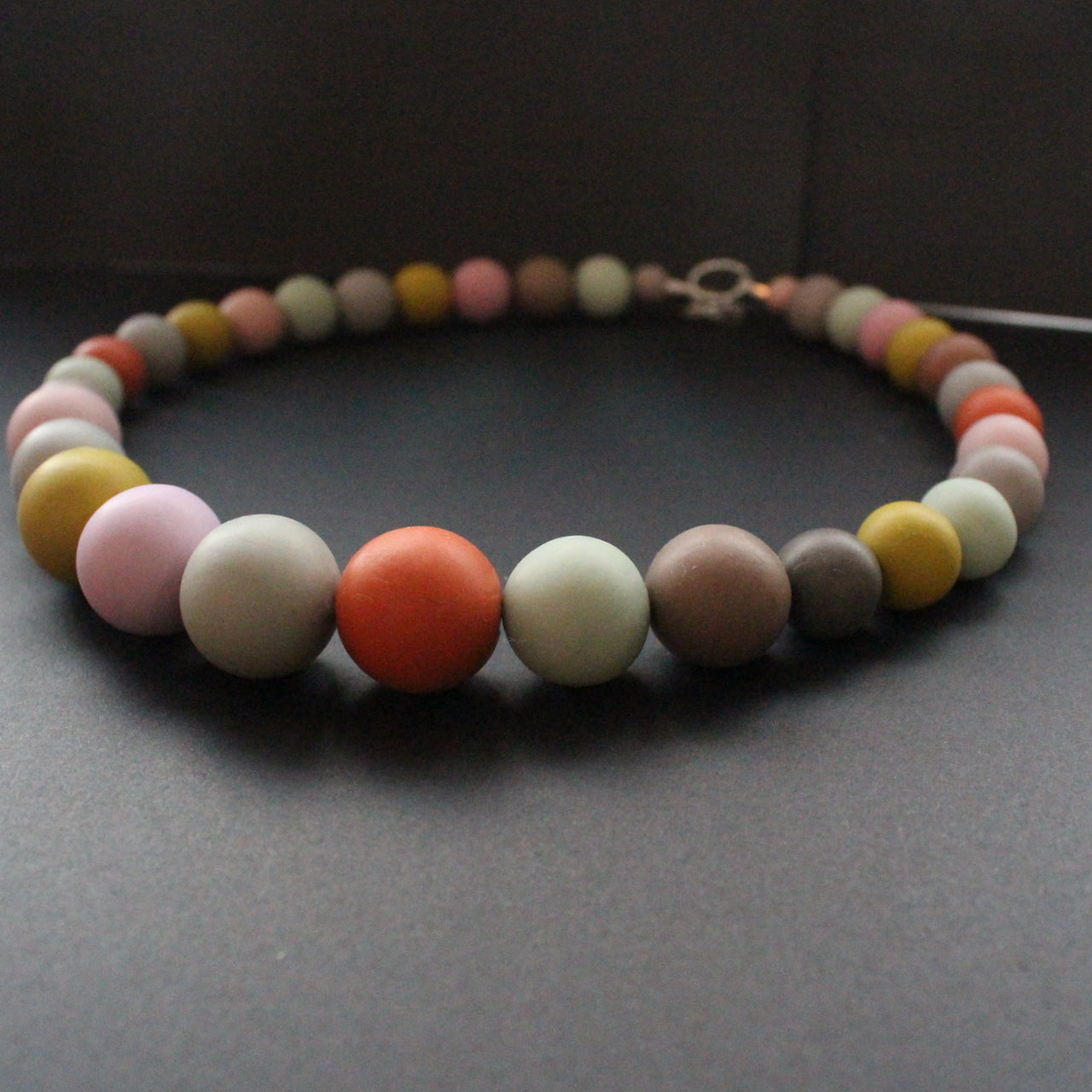 Graduated size round beaded necklace in muted earth tones by artist Clare Lloyd