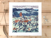 Framed lino print in blue tones with orange of robin sitting on a branch in the foreground and fields and trees in the background by Cornish artist Claire Armitage