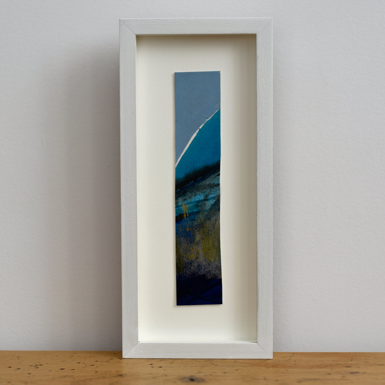 Abstract portrait picture of headland in dark blues and ochre with blue sky by Alice Robinson-Carter.