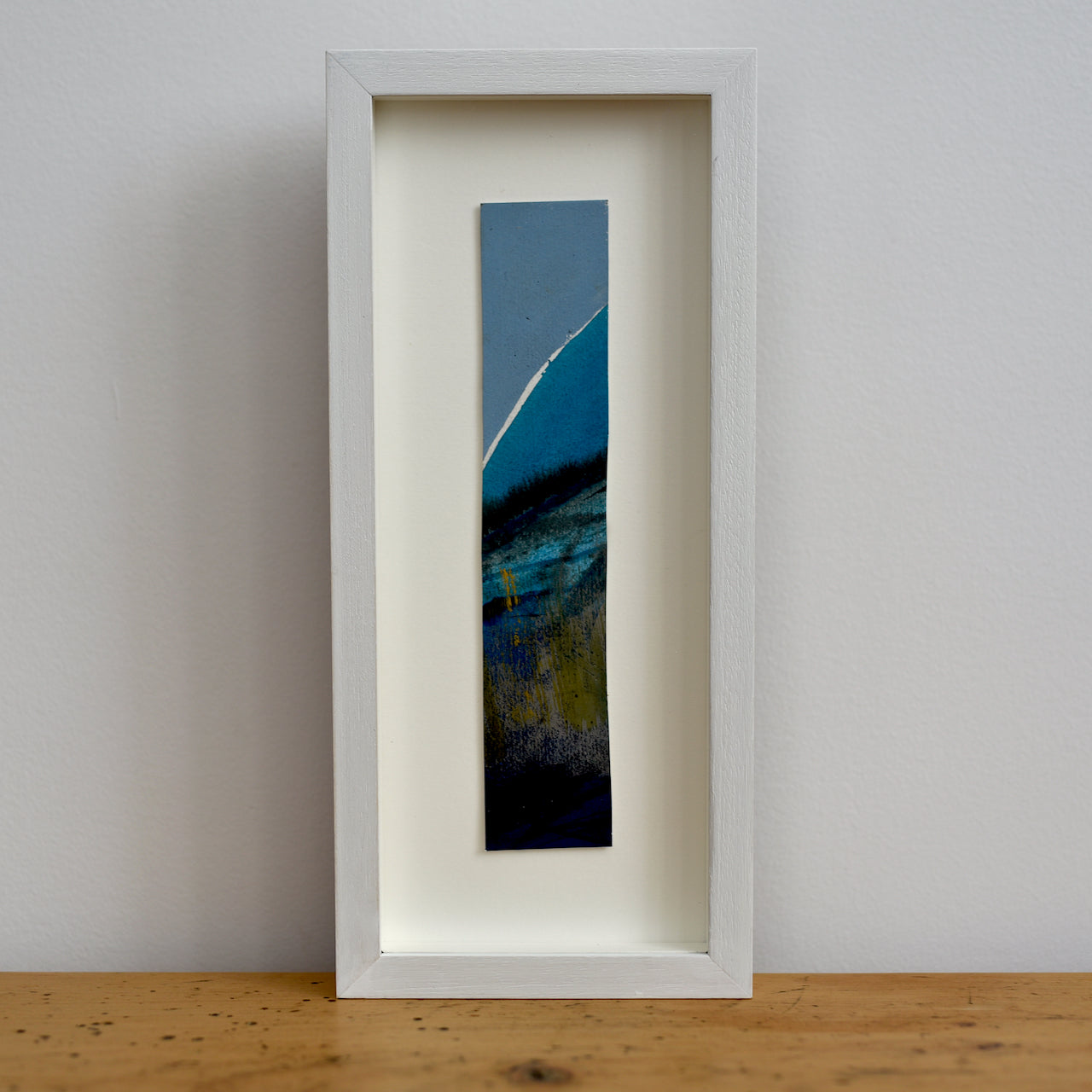 Abstract portrait picture of headland in dark blues and ochre with blue sky by Alice Robinson-Carter