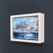 a framed Jill Hudson seascape of purple clouds in a pale blue sky over dark blue and white Sea