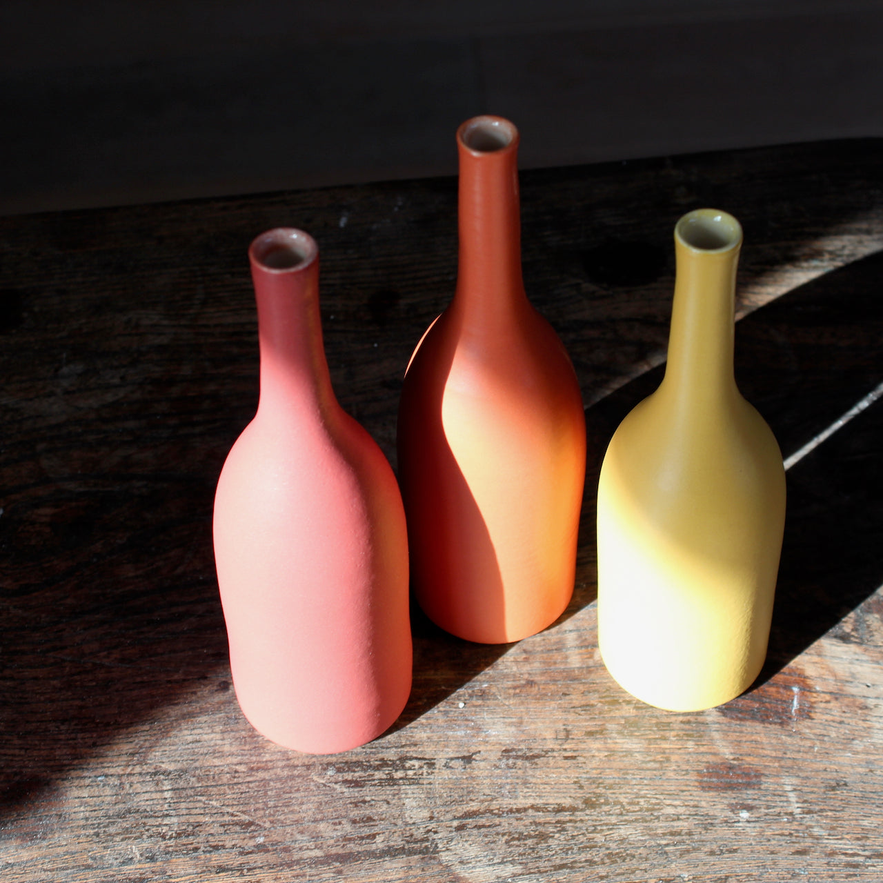a trio of  ceramic bottles in shades of yellow and orange by UK ceramic artist Lucy Burley