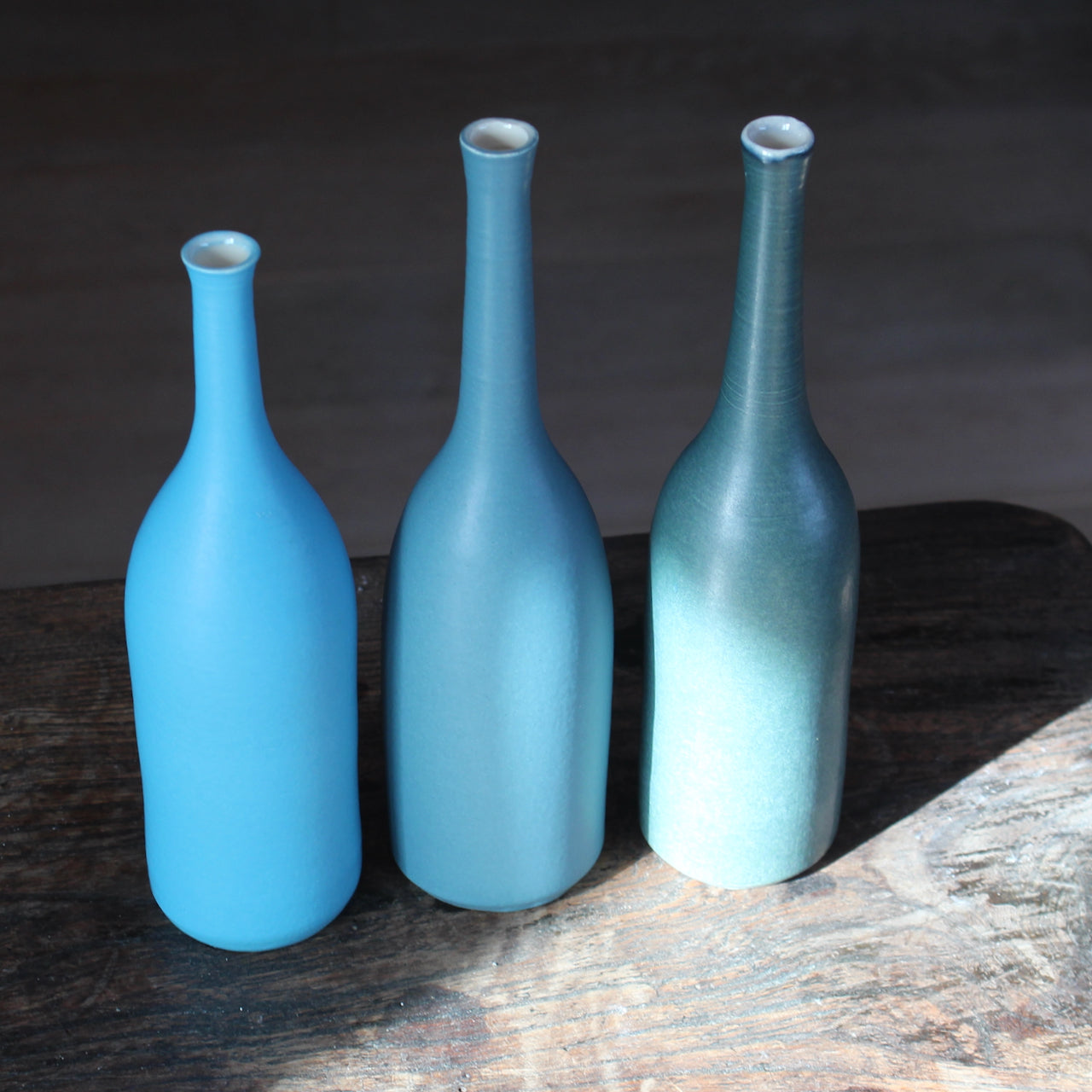 three ceramic bottles in shades of teal and blue by ceramic artist Lucy Burley
