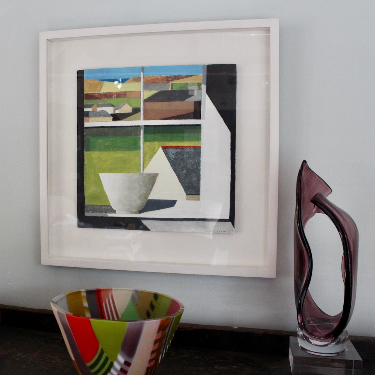 UK artist Philip Lyons, framed painting of white bowl on white window sill looking out to green landscape, houses and blue ocean in far distance.