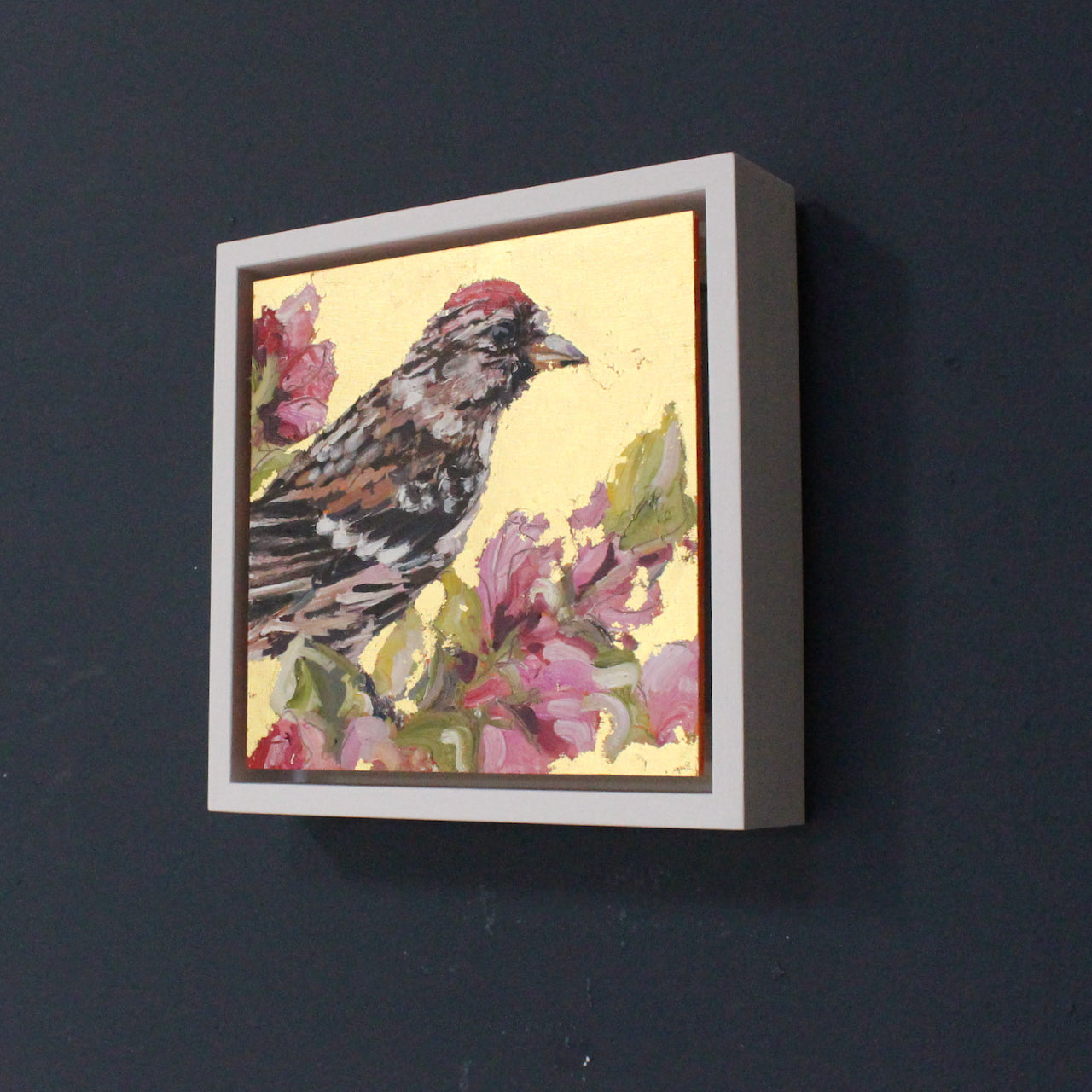 Square painting with redpoll on gold leaf background and pink blossom by artist Jill Hudson
