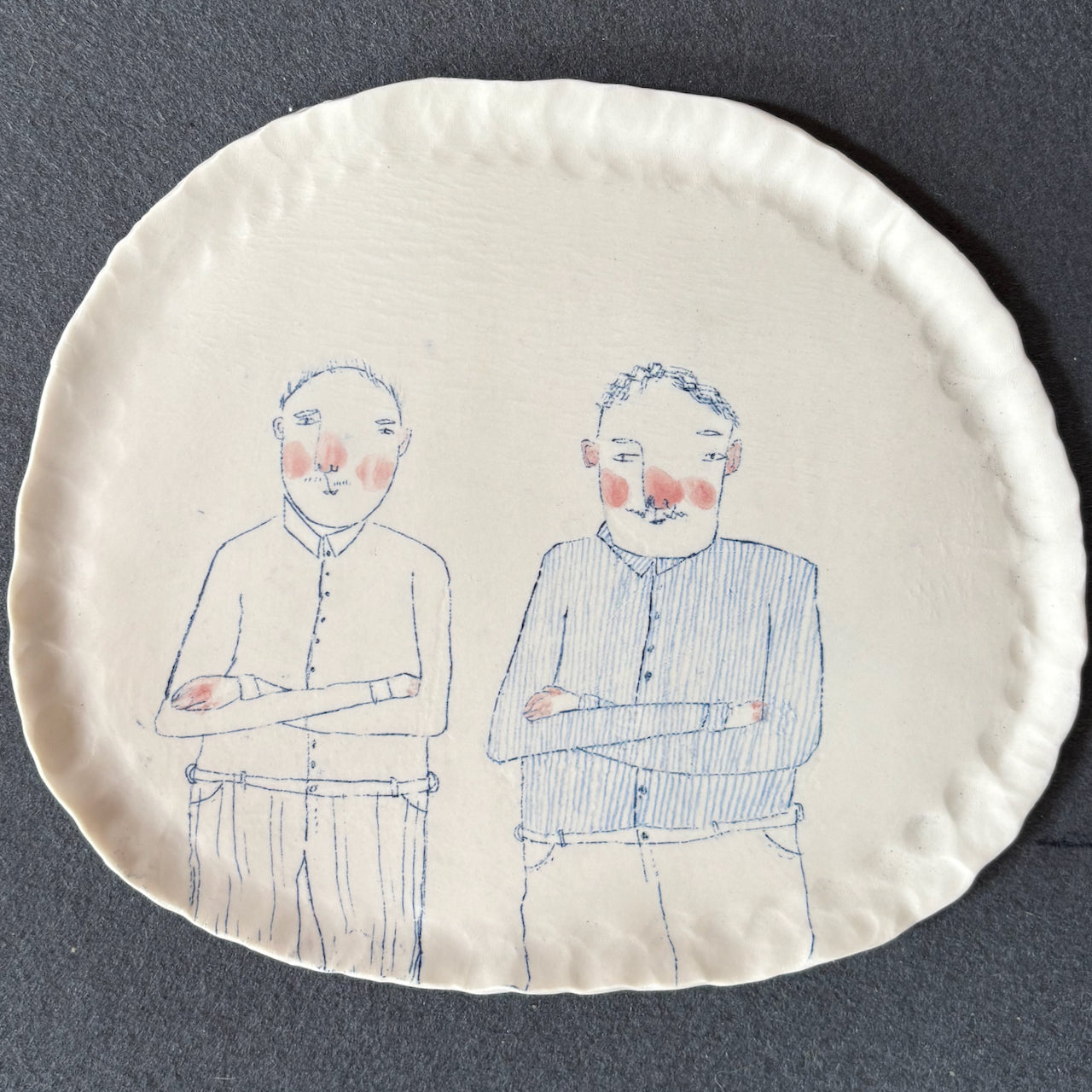 Becca Brown ceramic plate decorated with drawing of two men with their arms crossed