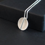 a textured silver disc pendant with a central bar by Uk jeweller Beverly Bartlett