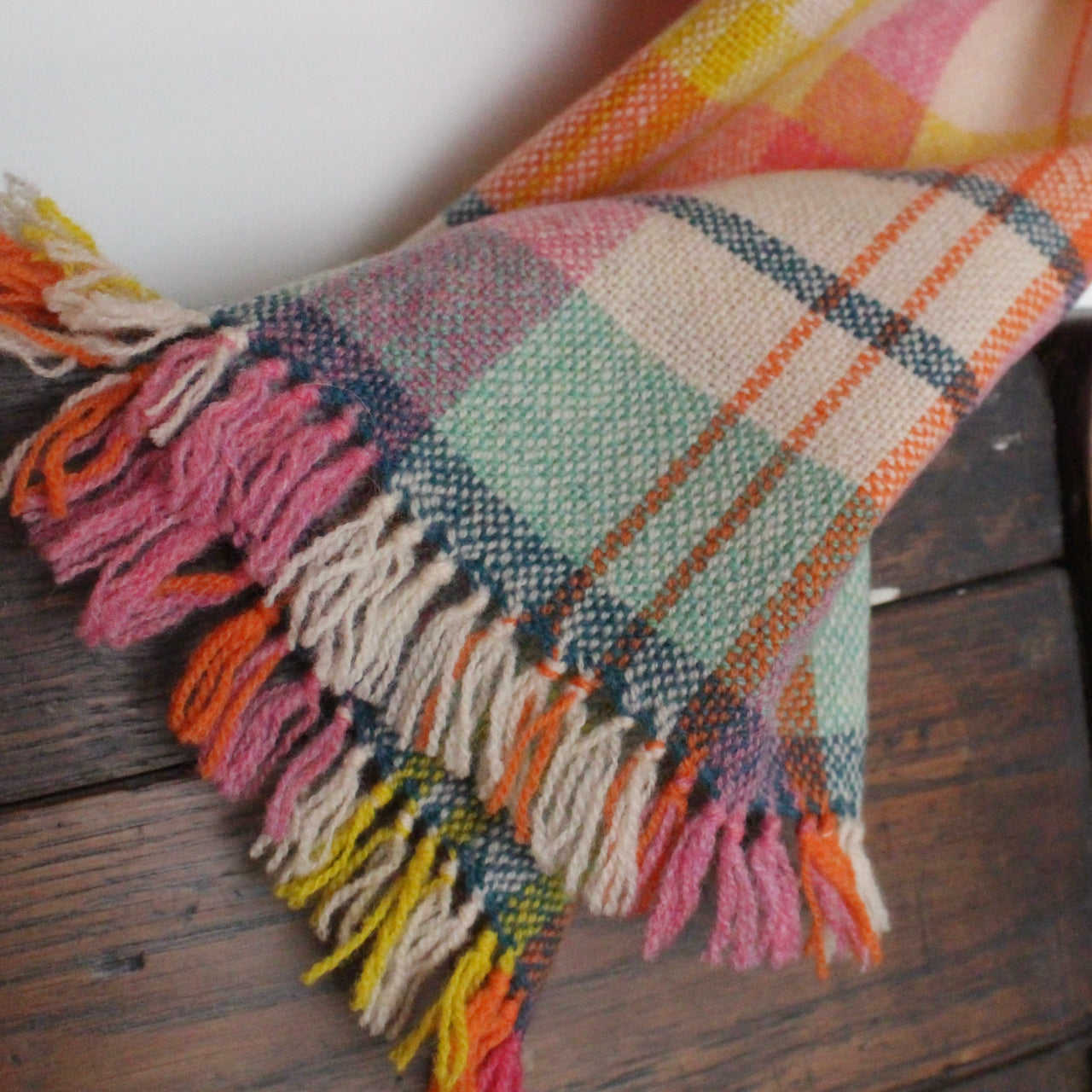 close up detail of a handwoven woollen scarf by Teresa Dunne Cornish weaver in pink, cream, orange and yellow.