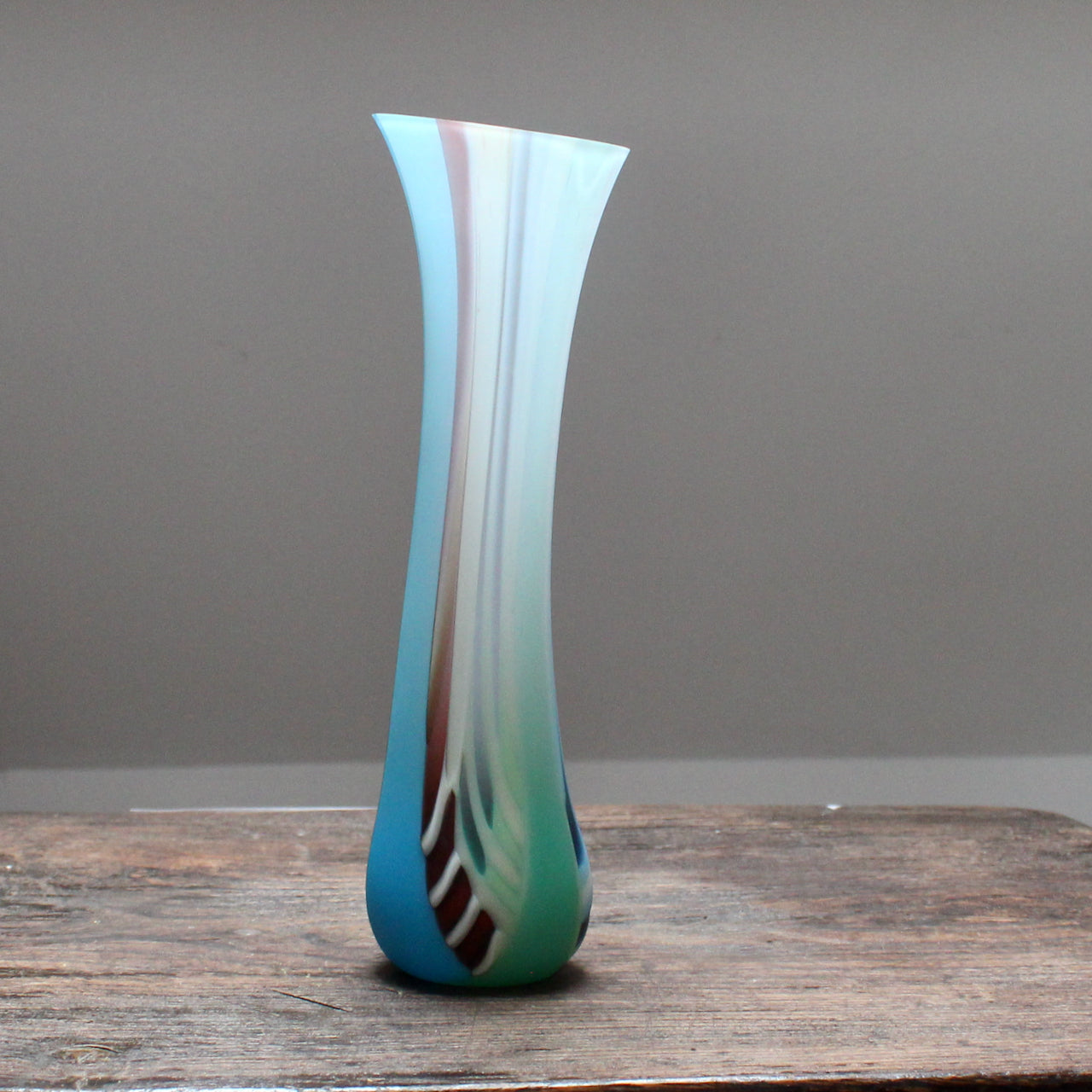 tall, slim multi-coloured glass vase with a slightly angled top made by glass artist Ruth Shelley