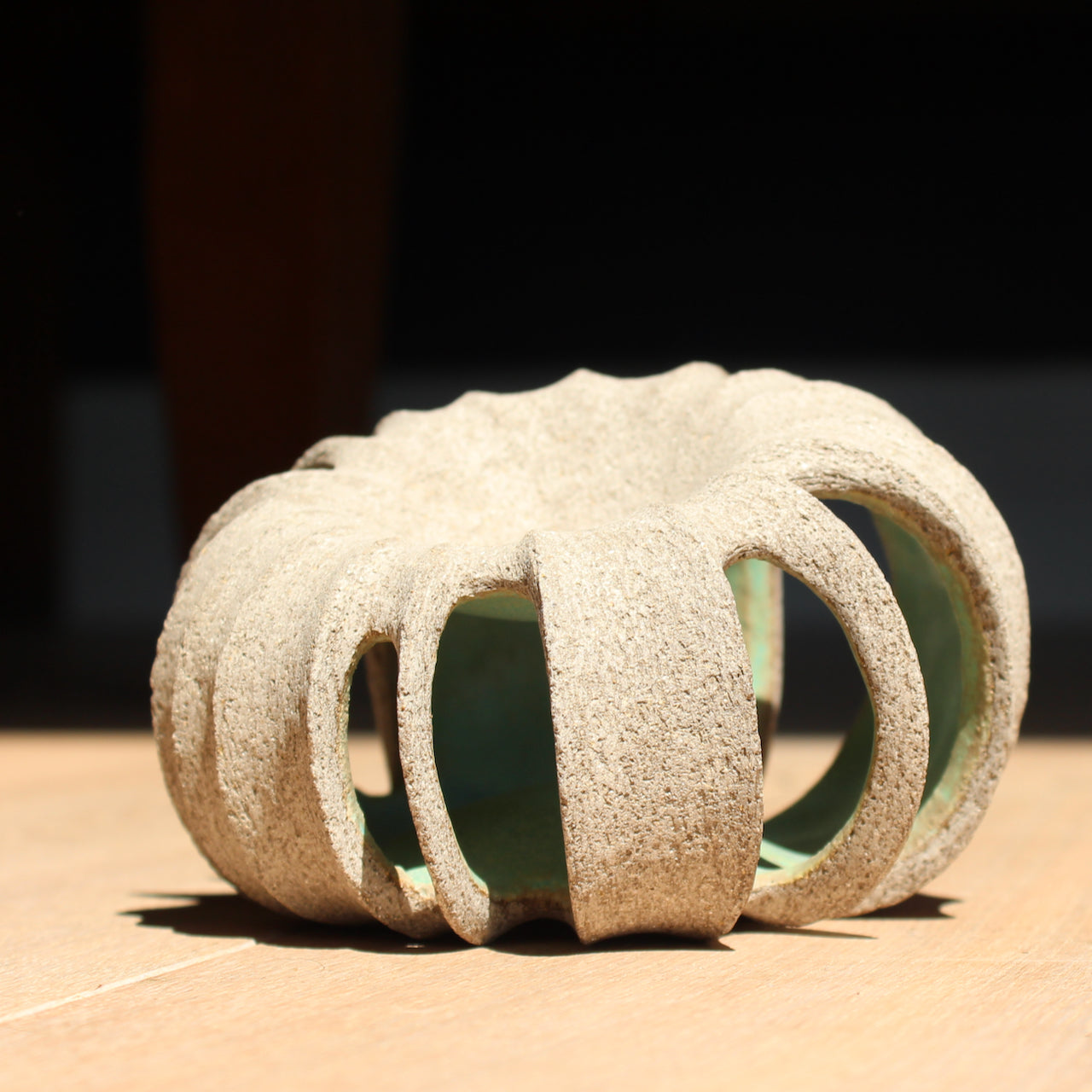 a small rounded stoneware sculpture hand carved with a pale green interior glaze by British ceramicist Michele Bianco