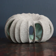 a small rounded stoneware sculpture hand carved with a pale green interior glaze by ceramicist Michele Bianco