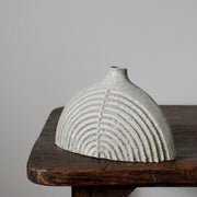 a small rounded and carved pale grey stoneware bottle by Michele Bianco.