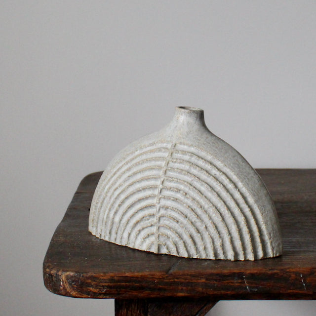 a small rounded and carved pale grey stoneware bottle by Michele Bianco.