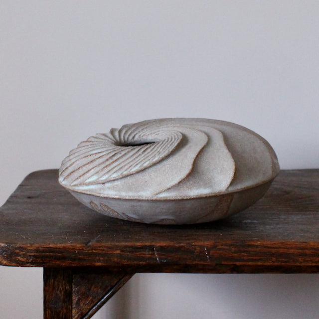 the side view of A round and carved ceramic vessel by Michele Bianco.