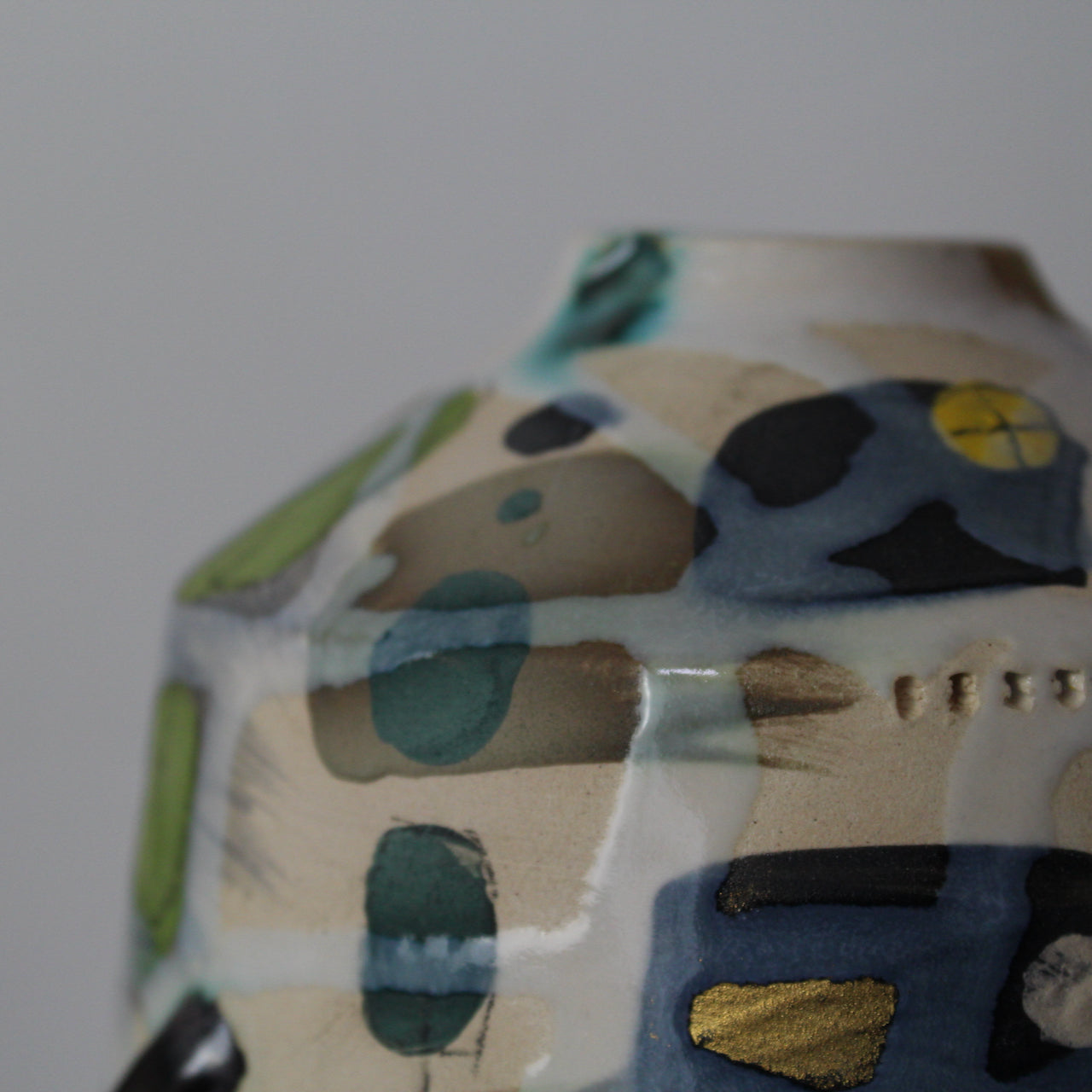 close up detail of a ceramic bottle in yellow, grey and green by UK potter Dawn Hajittofi