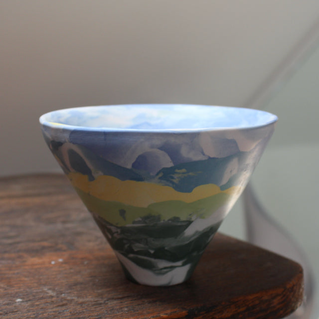 a small ceramic bowl in blue, yellow and green and black  by ceramic artist Judy Mckenzie.