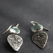 Textured silver with aquamarine stone drop earrings on a dark grey background