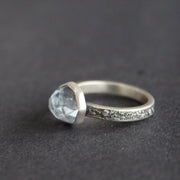 Textured silver ring with pale blue stone on a grey surface