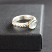 Moss aquamarine (oval) set in gold on textured ring in brushed silver by Carin Lindberg
