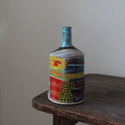 a multi-coloured ceramic bottle with a blue neck by John Pollex