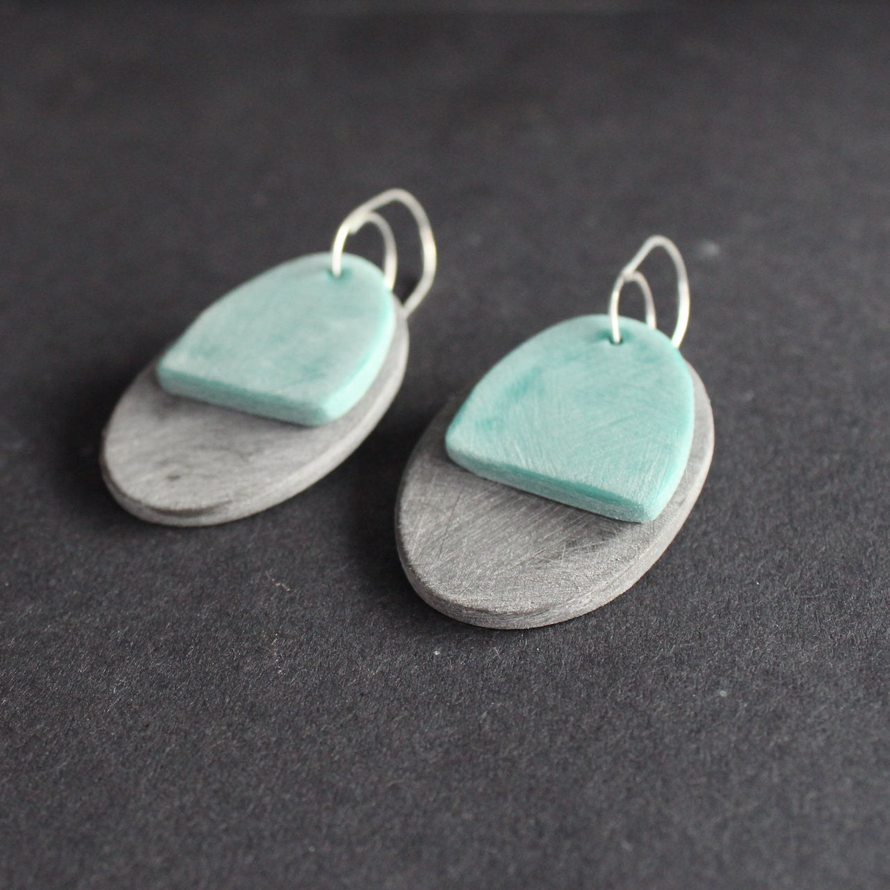 a pair of oval shaped earrings in grey and green by jewellery designer Clare Lloyd