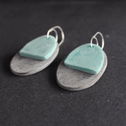 a pair of oval shaped earrings in grey and green by  Clare Lloyd.