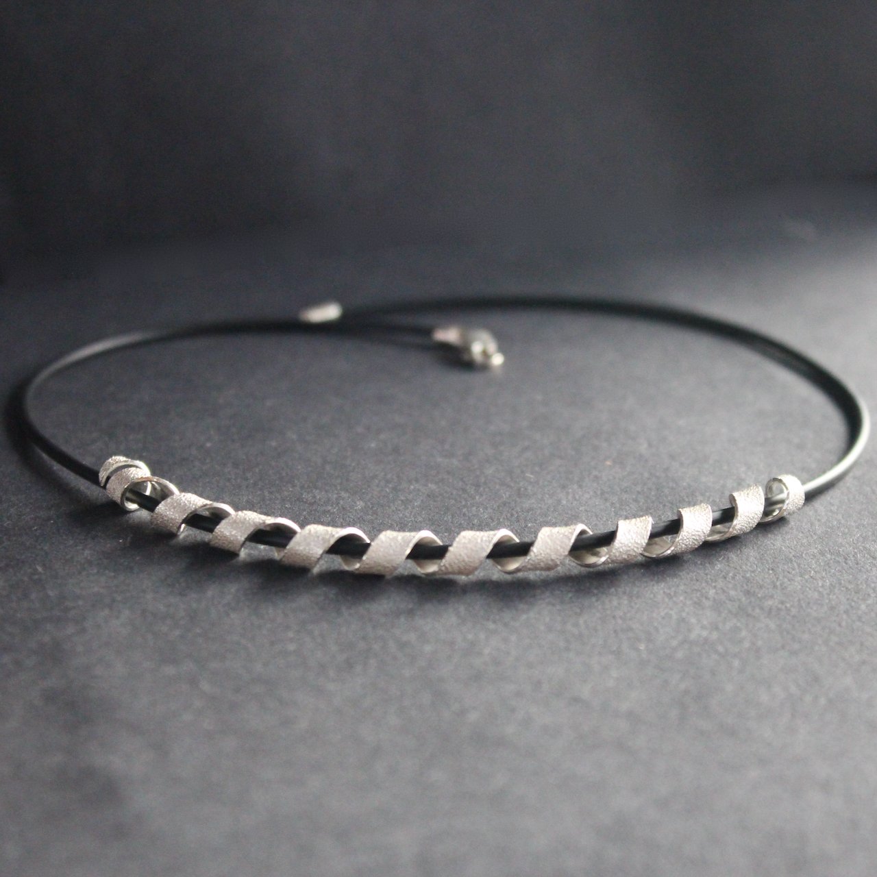 a silver helix twisted necklace on black leather band by Beverly Bartlett, UK jewellery designer