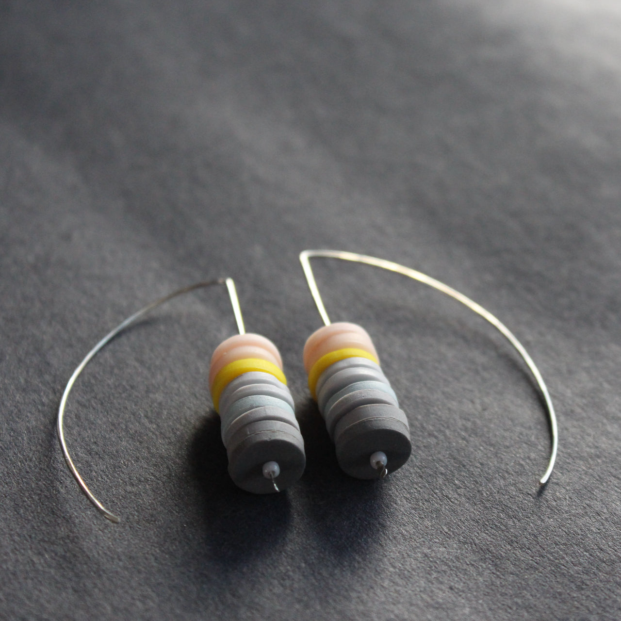 earrings made of small discs on top of each other in shades of grey and pink by jewellery designer Clare Lloyd