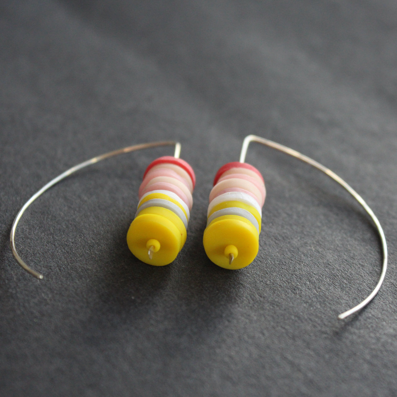 pair of earrings made of small discs on top of each other in yellow and shades of pink by UK jeweller Clare Lloyd