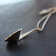 Side view of a textured silver curved and circular pendant on a silver chain