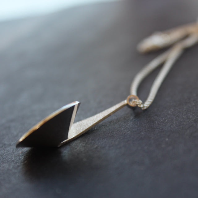 Side view of a textured silver curved and circular pendant on a silver chain