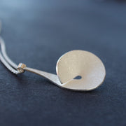 The Byre Gallery pyriform pendant by Beverly Bartlett - it is a Textured silver curved and circular pendant on a silver chain