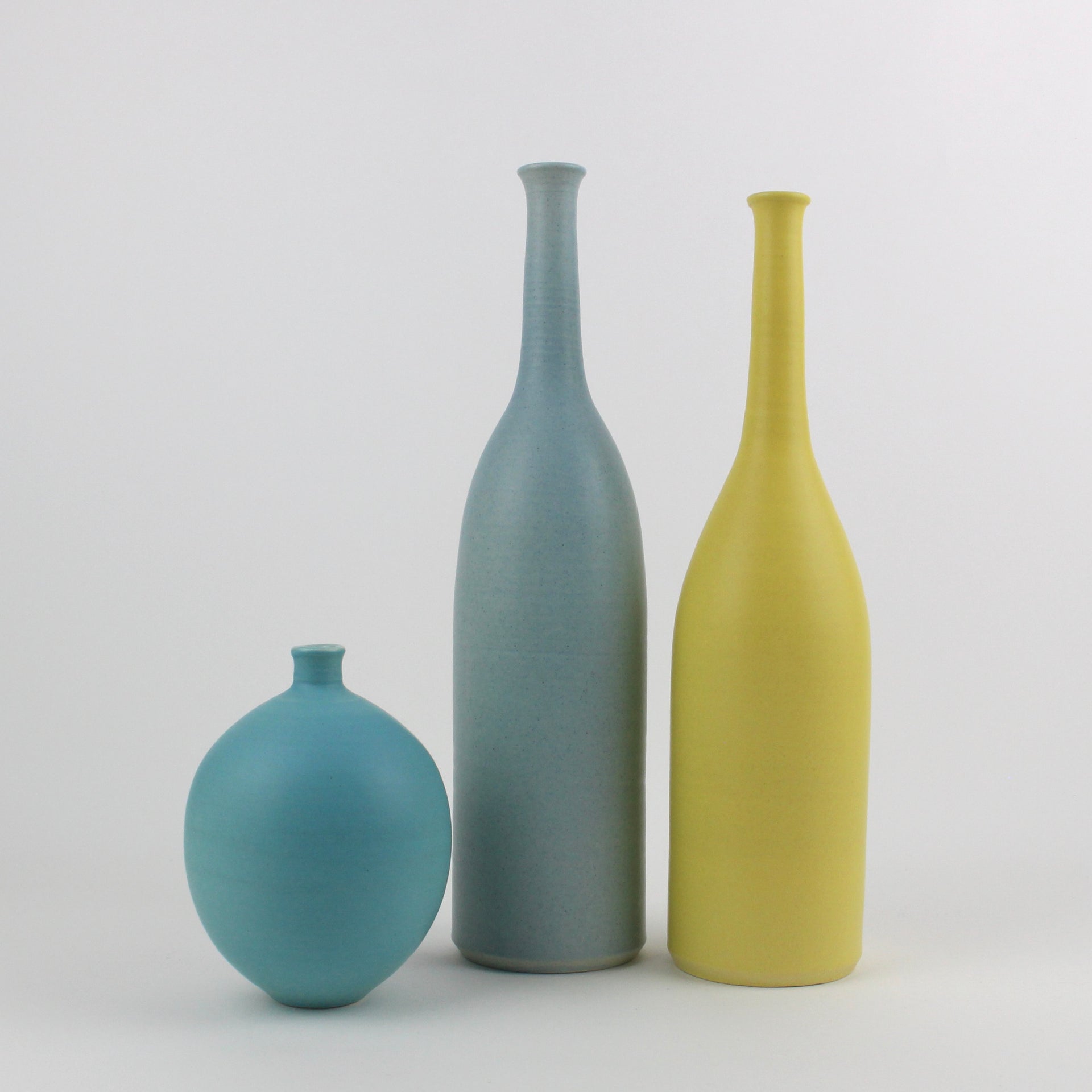 three ceramic bottles in blue, yellow and turquoise made by UK ceramic artist Lucy Burley.