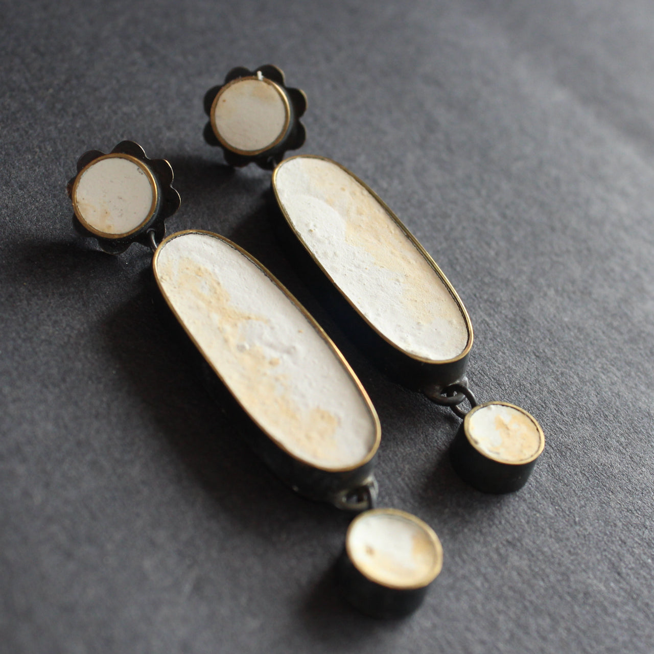 A classic pair of earrings made from blackened brass, cement and a silver pin by Amy Stringer