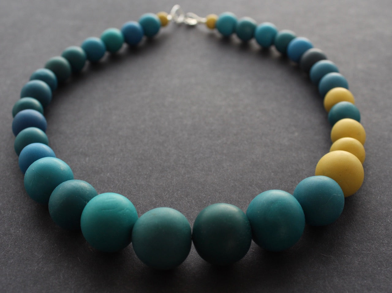 Graduated bead necklace with teal blues, greens and yellow by Clare Lloyd