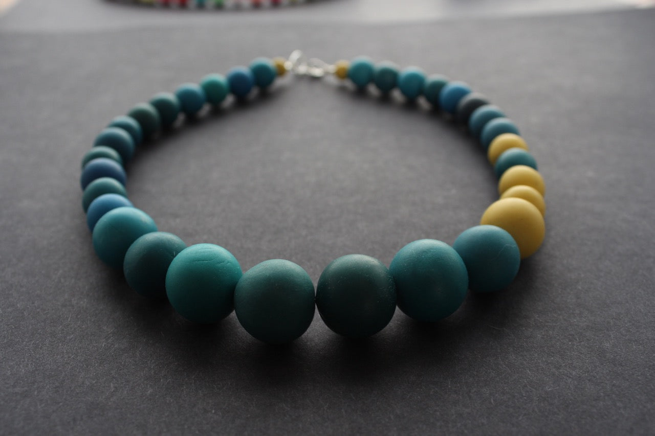 Graduated bead necklace with teal blues, greens and yellow by Clare Lloyd