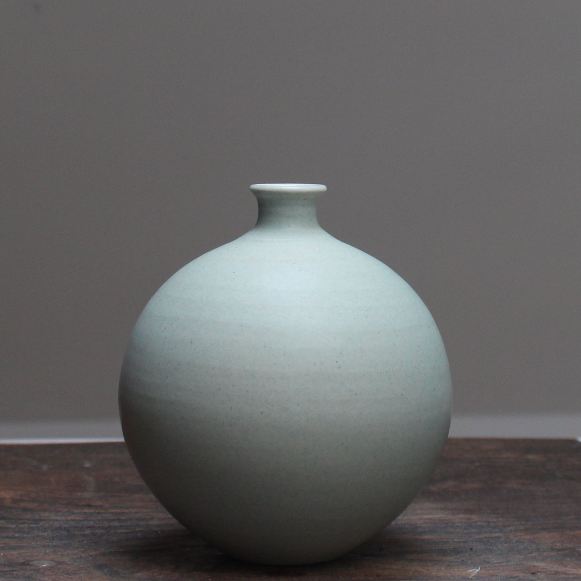 Light green round ceramic bottle by Lucy Burley, on a wooden table at the Byre Gallery