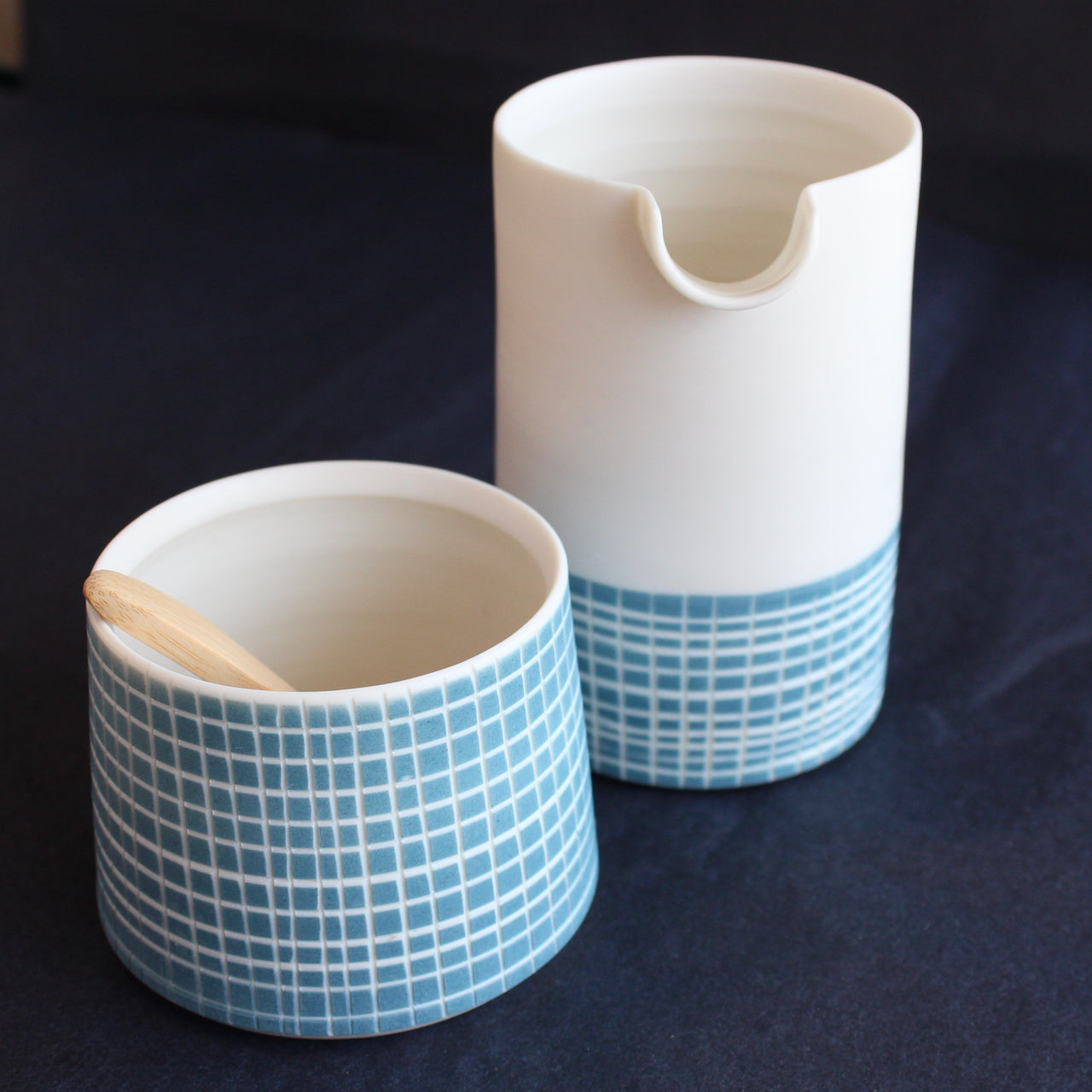 a porcelain pourer and condiment bowl set by Kathryn Sherriff of By the Line Pottery each is designed with a blue cross hatch glaze.