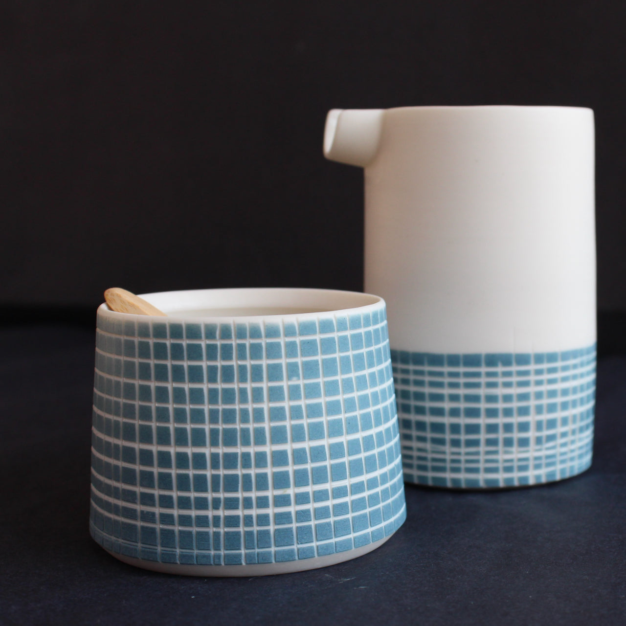 a a porcelain pourer and condiment bowl by Kathryn Sherriff of By the Line Pottery decorated with a blue cross hatch glaze design.