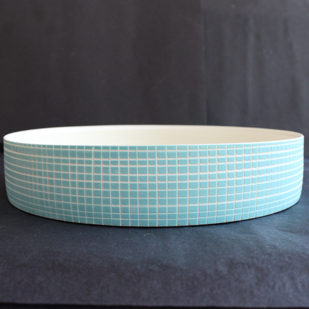 a round ceramic serving dish with blue cross hatch design by Kathryn Sherriff of By the Line Pottery