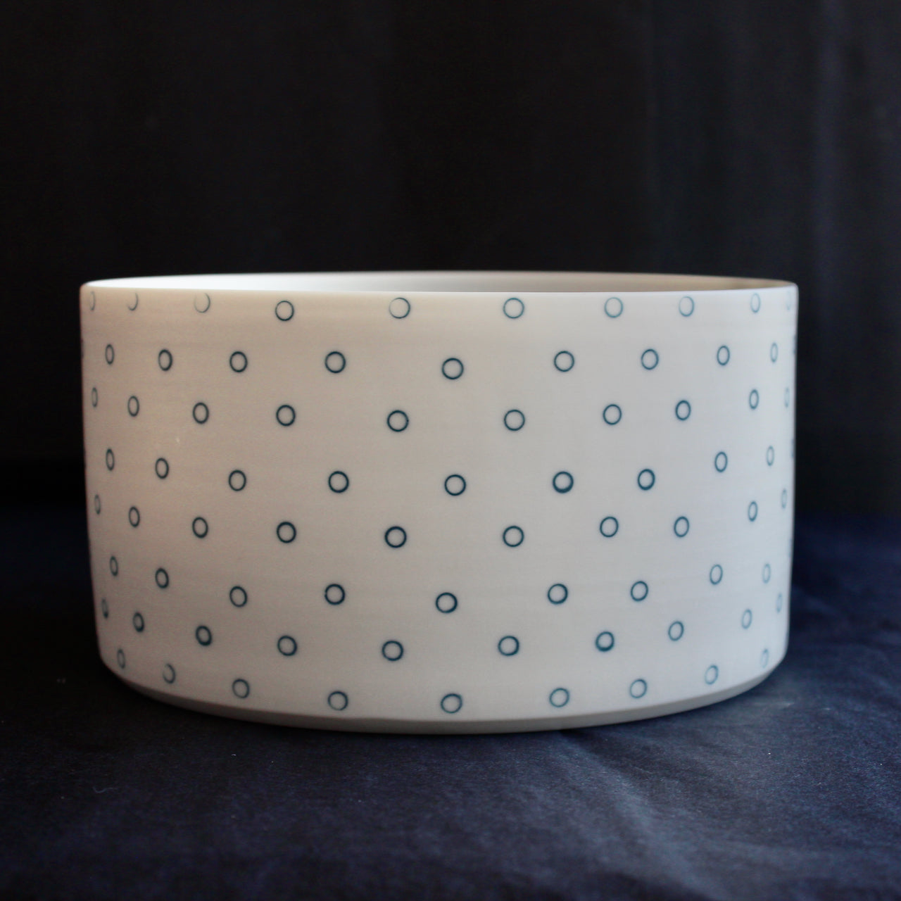 a deep porcelain serving dish by Kathryn Sherriff of By the Line Pottery it  is decorated on the exterior with small blue circles