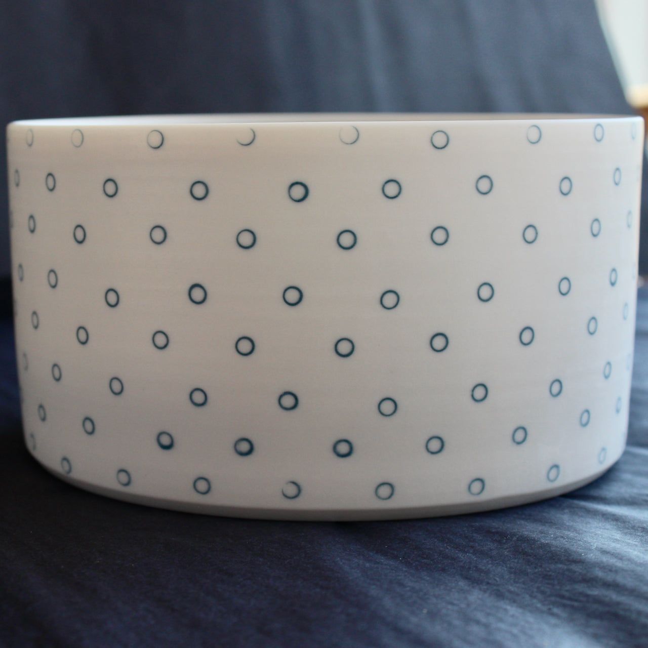 close up of a deep porcelain serving dish by Kathryn Sherriff of By the Line Pottery it is decorated on the exterior with small blue circles