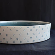 close up detail of a porcelain serving dish by Kathryn Sherriff of By the Line Pottery with a blue interior and a blue circle design on the exterior