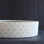 close up of a porcelain serving dish by Kathryn Sherriff of By the Line Pottery with a blue interior and a blue circle design on the exterior.