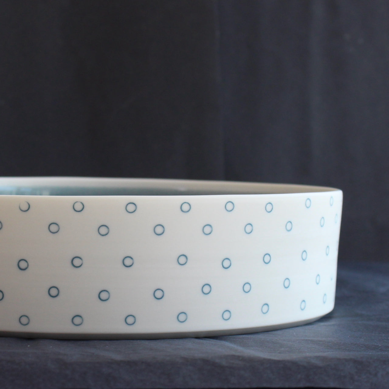 close up of a porcelain serving dish by Kathryn Sherriff of By the Line Pottery with a blue interior and a blue circle design on the exterior.