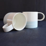 two espresso style cups by Kathryn Sherriff of By the Line Pottery they are in white porcelain with a turquoise ring design around the bottom half